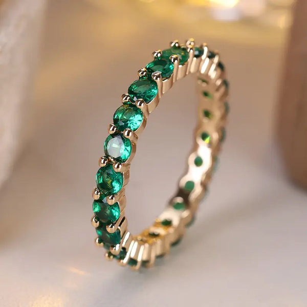 Goudkleurige eternity ring met smaragdgroene steentjes