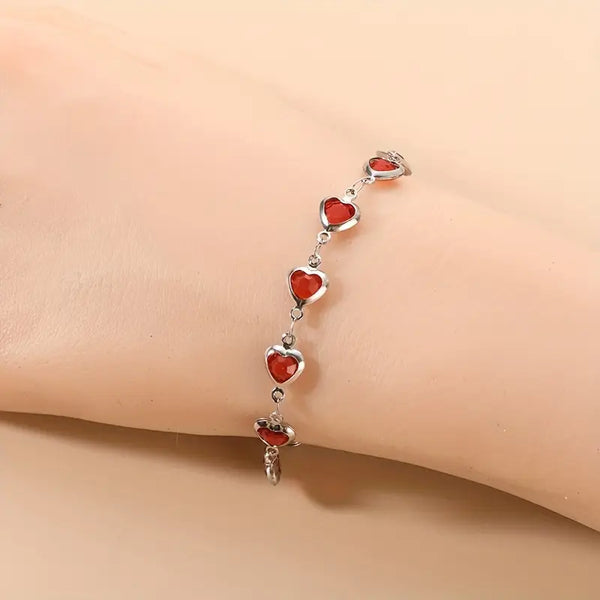 Zilverkleurige schakelarmband met robijnrode hartjes