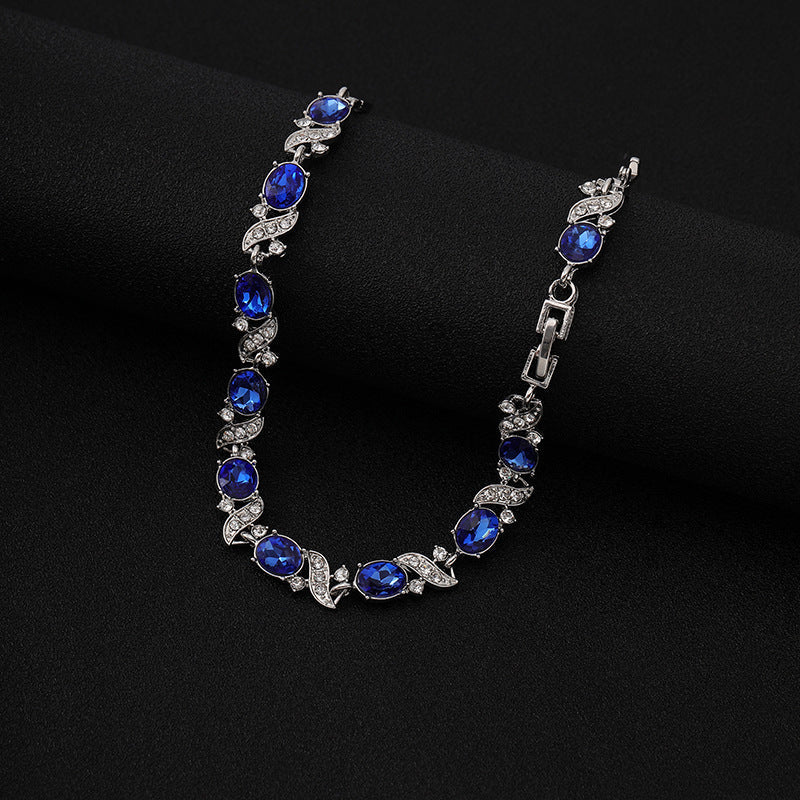 Zilverkleurige schakelarmband met saffierblauwe stenen en bloemetjes
